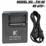 FOTOKINA digital camera battery charger (Model FW-50) for Sony NP-FW50 type batteries, shown next to its black AC power cable. The charger is black and features the FOTOKINA logo. Text overlays indicate 'MODEL NO - FW-50' and the price 'RS 672/-'.